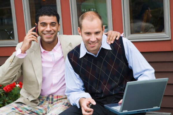 Businessman talking on a mobile phone with another businessman sitting beside him